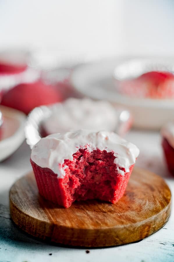 A single red velvet cupcake with a bite taken out